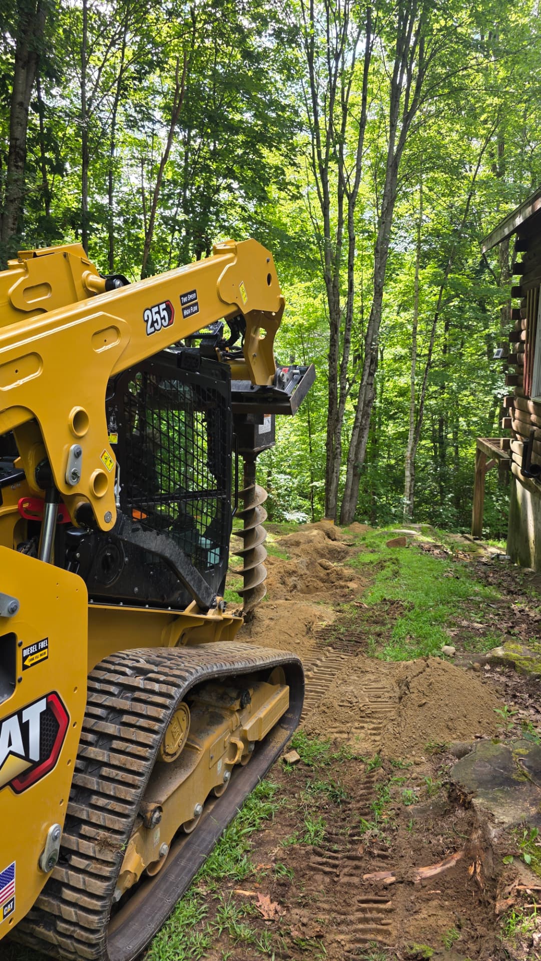 Auger work along a wooded hillside access path